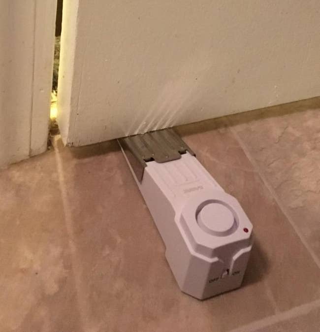 a reviewer photo of the wedge alarm inserted underneath a door