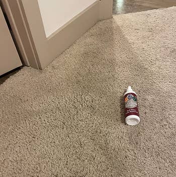 reviewer after photo of their carpet looking stain-free, with a bottle of the wine away stain remover
