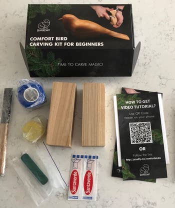 Bird carving kit for beginners with included tools: wood blocks, carving tools, tape, sandpaper, and instructional pamphlet