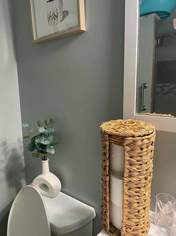 Bathroom with a wicker handbasket  holding toilet paper, a tiny  works  successful  a achromatic  vase, and a framed representation   connected  the wall