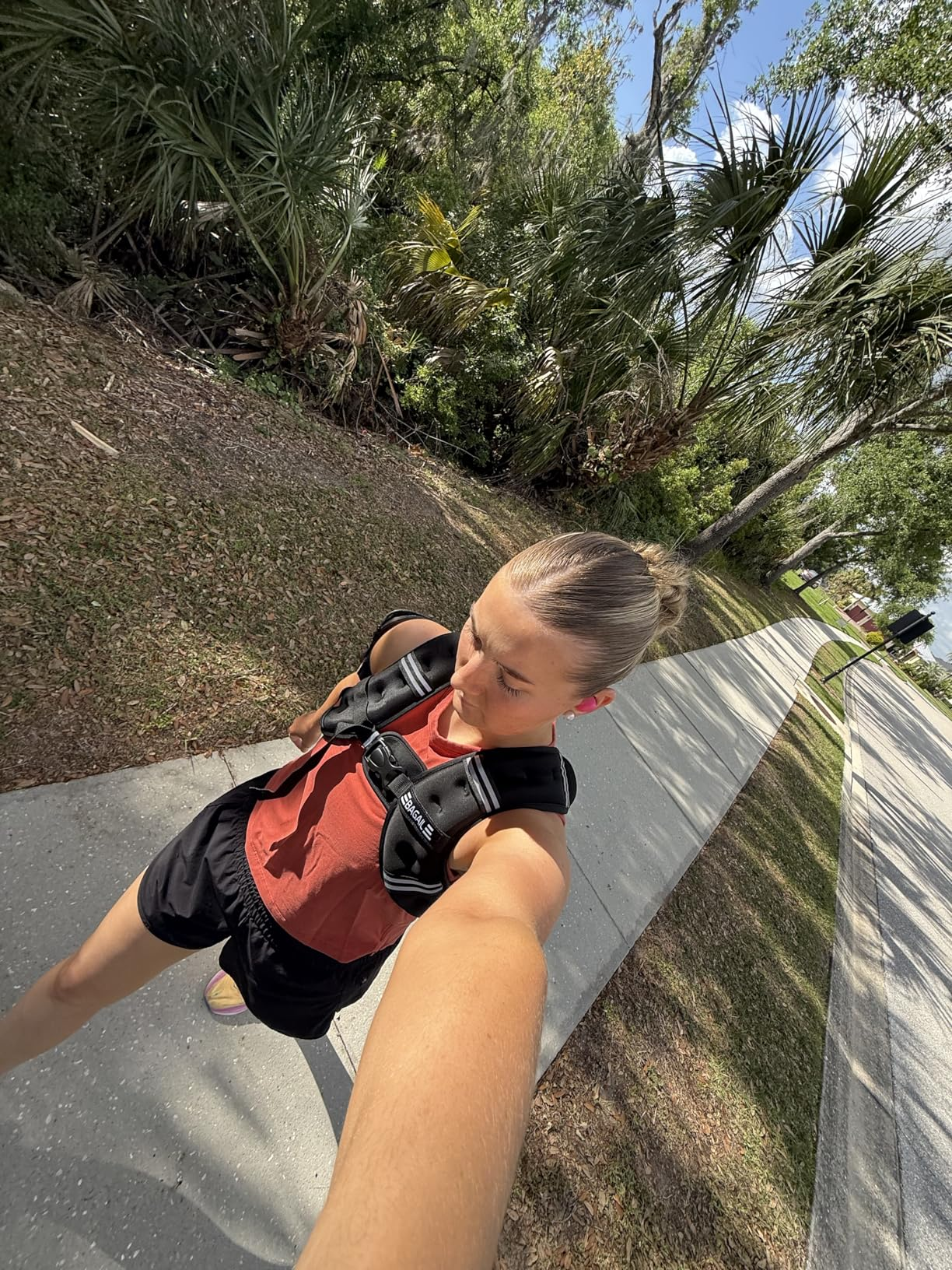 Person taking a selfie portion    walking outside, wearing a casual reddish  apical  and achromatic  shorts with a fittingness  harness oregon  backpack