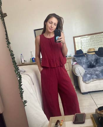 reviewer in a sleeveless red peplum top and pant set  