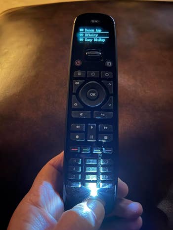 Reviewer holding down the thumb light attached to a TV remote