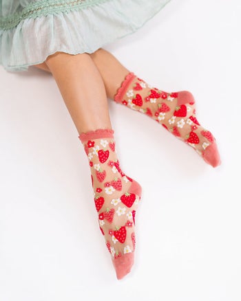 model wearing sheer socks that have red strawberries and hearts stitched on them