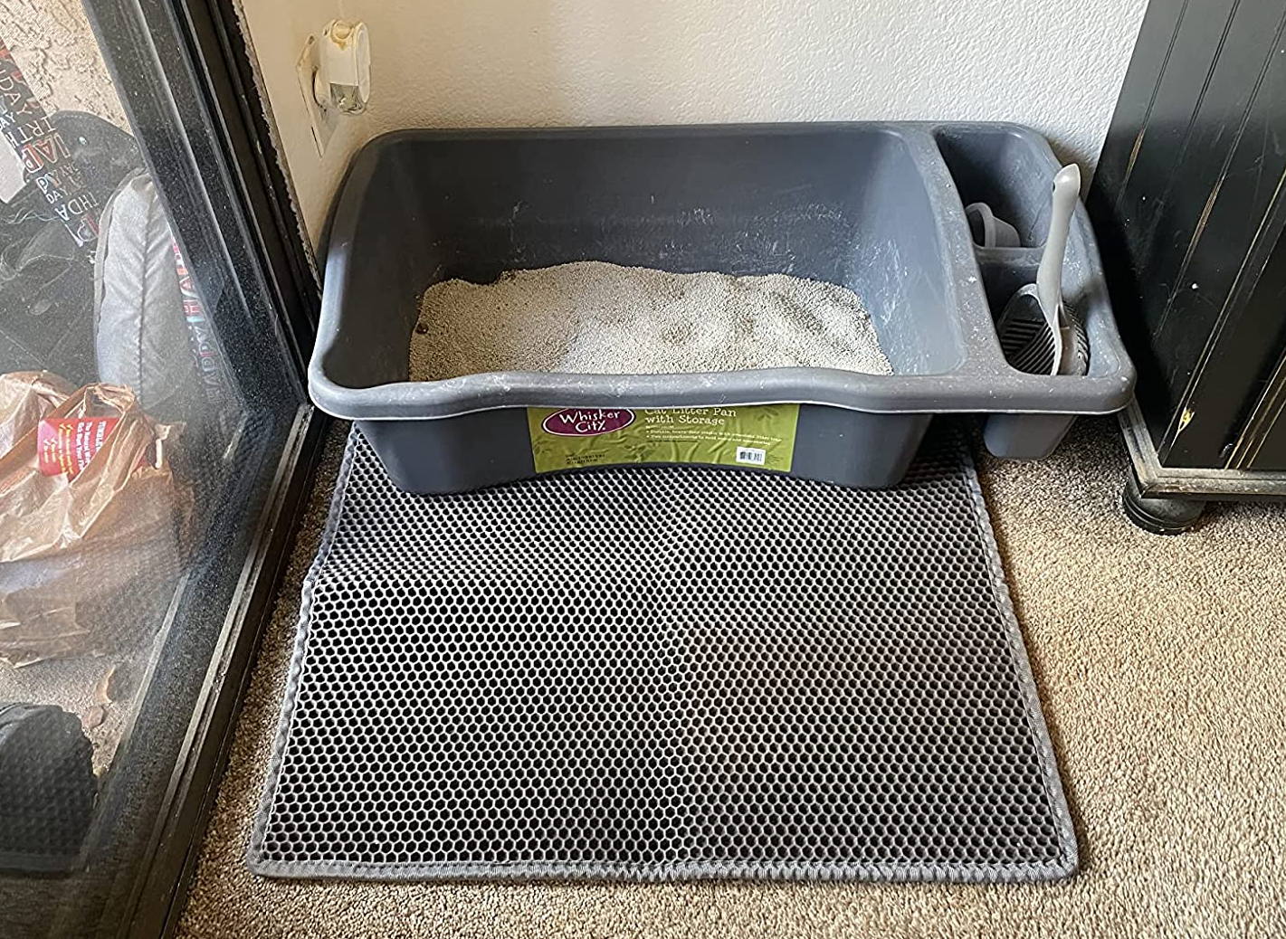 a reviewer photo of a litter box sitting on  gray honeycomb mat 