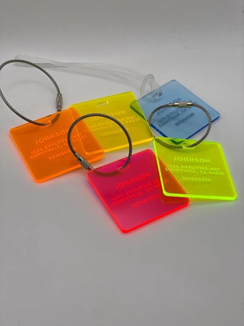 all five color options for the luggage tag, including neon green, pink, orange, yellow, and blue