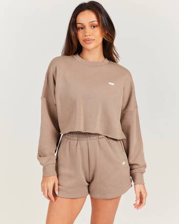 A idiosyncratic wearing a taupe cropped sweatshirt and matching shorts, styled casually
