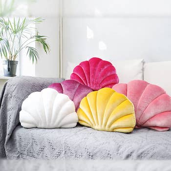 pink, white, and yellow seashell-shaped pillows on gray couch