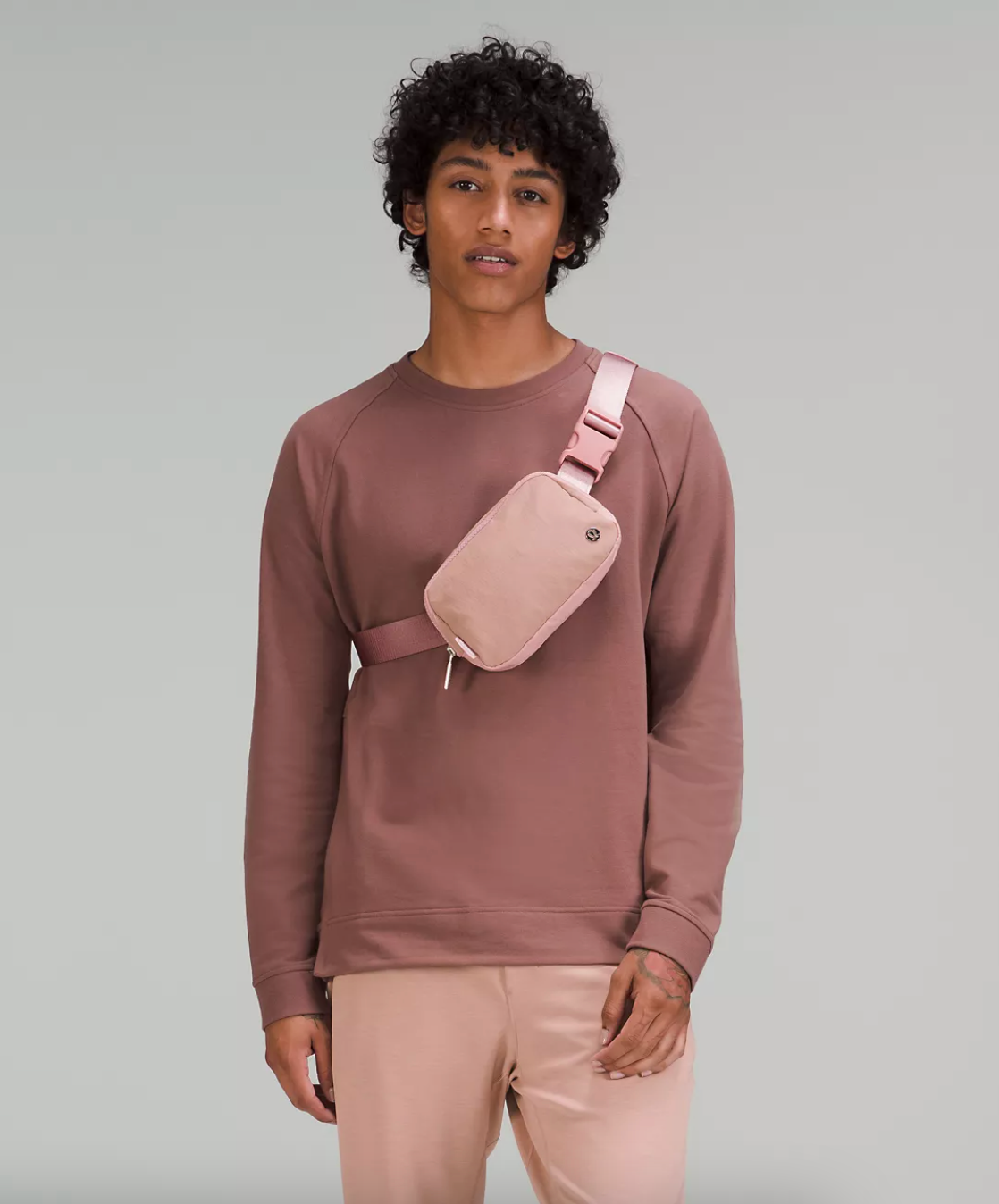 model wearing the light pink belt bag across their chest