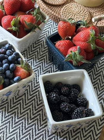 Strawberries, blueberries, and blackberries are displayed successful  decorative bowls connected  a textured surface, suitable for a fruit-themed buying  article
