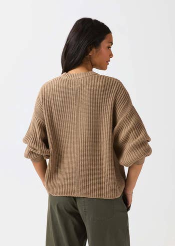 Person wearing a loose, ribbed knit sweater and relaxed-fit pants, viewed from behind