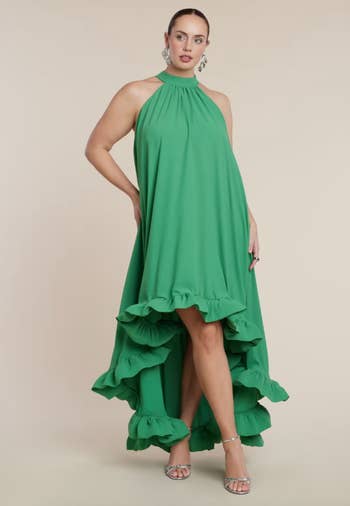 A idiosyncratic   models a flowy, high-low greenish  formal  with ruffled hem and halter neckline, styled with metallic  earrings and sandals