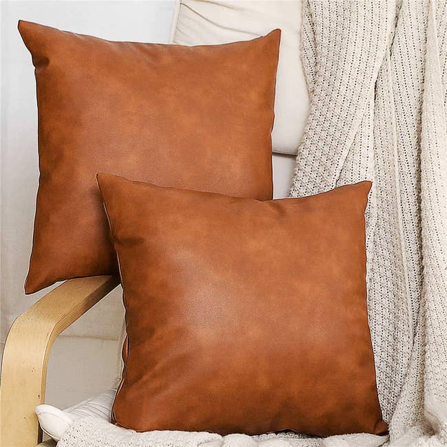 two pillows with brown faux leather pillowcases