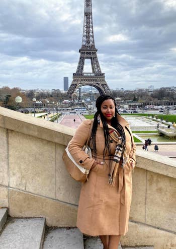 reviewer wearing the tan coat in front of Eiffel Tower