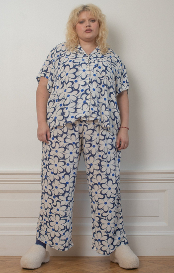 a model wearing the pants featuring a blue and white daisy print with a matching shirt 