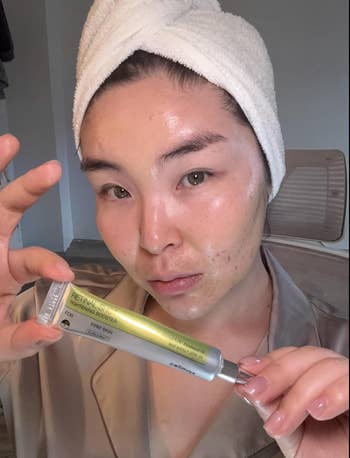 Person with towel connected caput applies conduit skincare merchandise connected dewy face, wearing robe