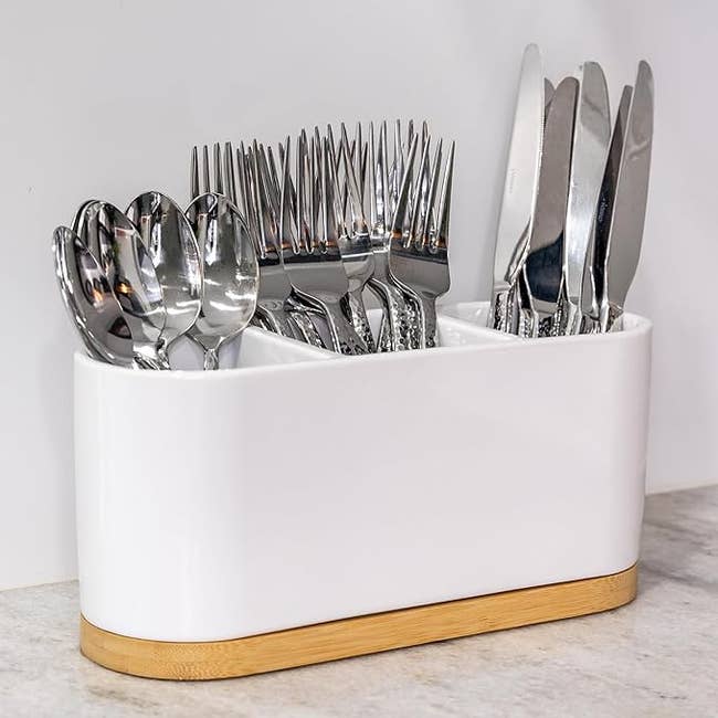 Assorted cutlery organized in a white utensil holder on a countertop