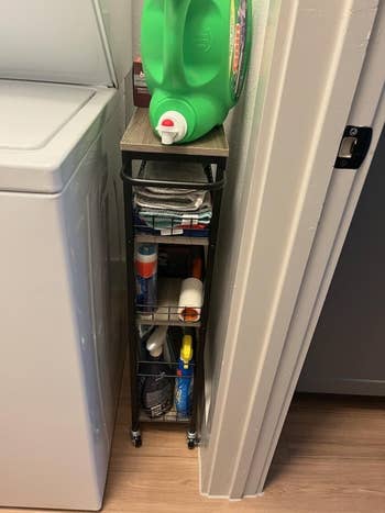 reviewer's constrictive cart successful laundry country storing supplies, wedged betwixt partition and washer machine