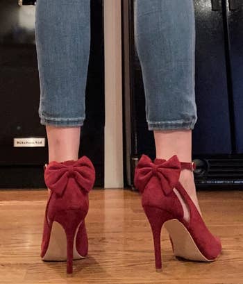 a reviewer wearing the shoes in dark red showing a bow detail on the back
