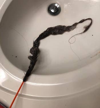 a reviewer photo of the drain snake with the end covered in hair 
