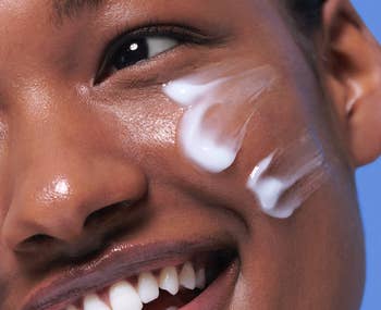 Close-up of a smiling idiosyncratic applying pick to their cheek, illustrating skincare application