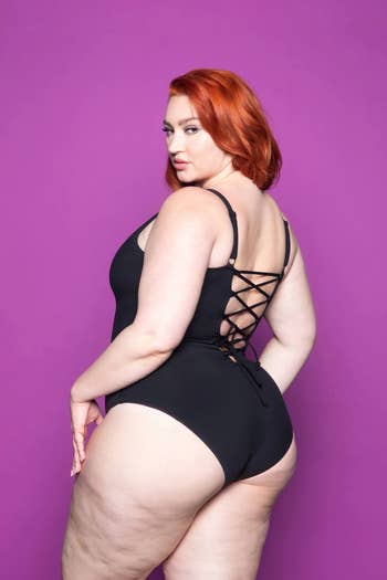 plus size model showing the lace up back of swimsuit in black
