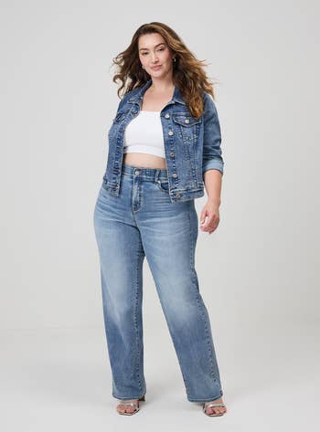 Person wearing a denim overgarment   with matching jeans, achromatic  harvest  top, and heels, posing confidently for a shopping-themed article