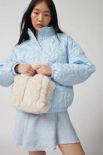 model holding a white fuzzy tote