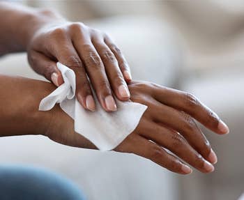Close-up of hands using a wet wipe, text reads: