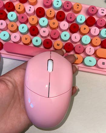 reviewer holding the pink mouse in front of the pink keyboard