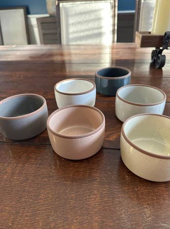 Six ceramic bowls successful varying pastel shades connected a woody table. Suitable for serving oregon decor successful a modern eating setting