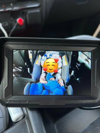 A babe is sleeping successful a car seat, covered with a blanket. The representation is viewed via a car's screen