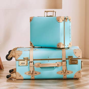 Blue rolling trunk and briefcase with accents of of a cream beige color 