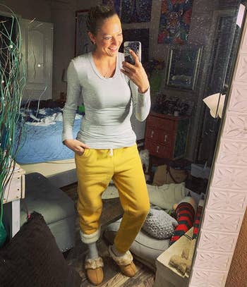 Person successful  a casual setting, wearing a long-sleeve top, comfy joggers, and slippers, taking a reflector  selfie. Cozy location  manner  vibe