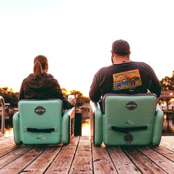 back of two people sitting in two of the teal inflatable aero chairs in different sizes