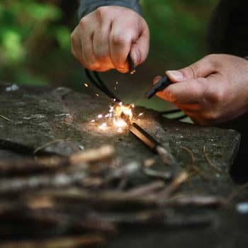 a person sparking a fire with the necklace