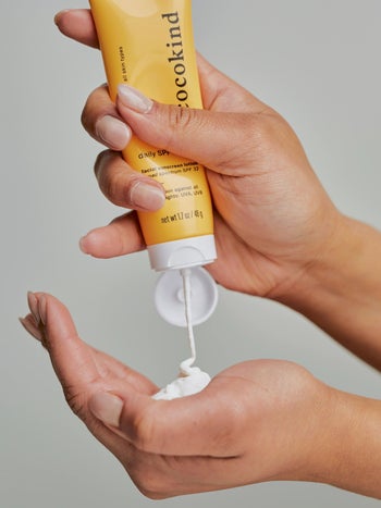 model squeezing sunscreen into their hand from the yellow tube