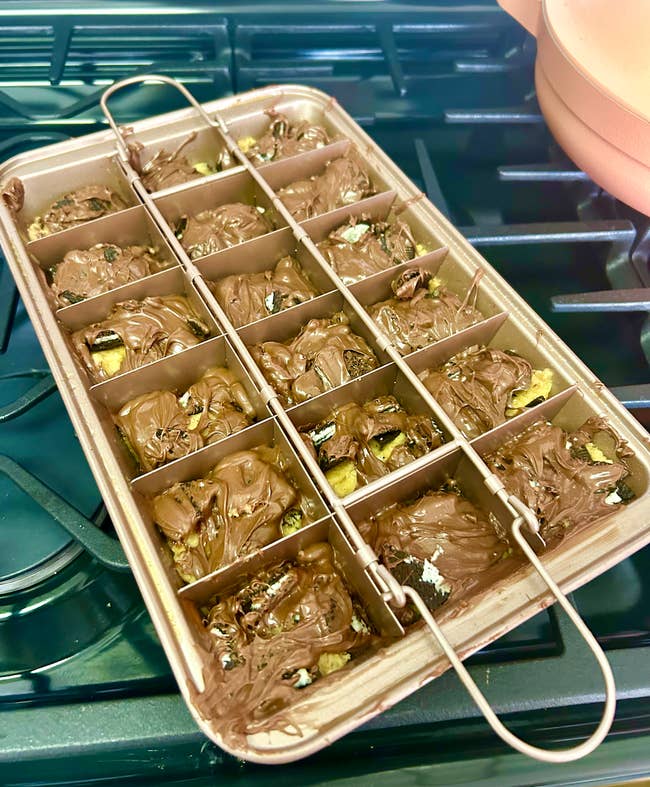 A copper colored pan with brownies in it divided into 18 slots with a removable divider on top 