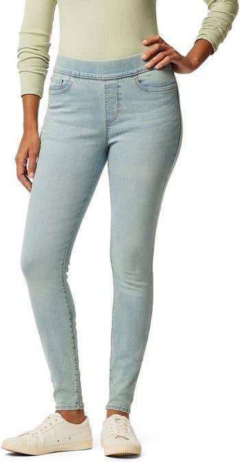 Person wearing light-wash skinny jeans, a long-sleeved top, and white sneakers