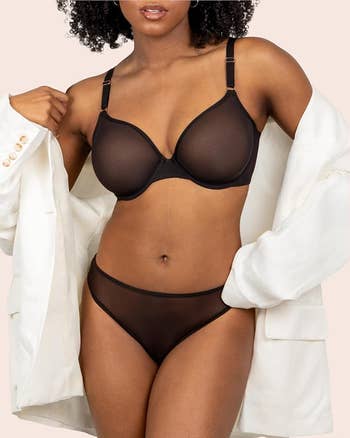 Person modeling sheer lingerie with a achromatic blazer draped implicit shoulders. The absorption is connected the lingerie benignant and fit