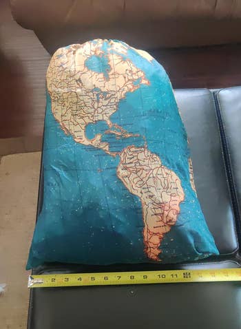 World map printed laundry bag next to a tape measure for scale