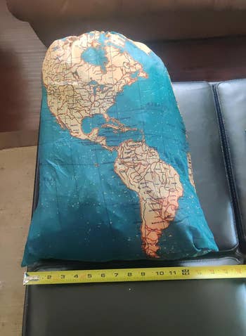 World map printed laundry bag next to a tape measure for scale