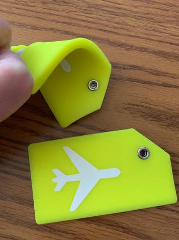 reviewer photo of neon yellow silicone luggage tag, bending it