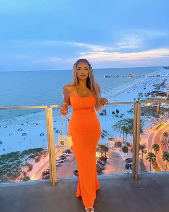 reviewer posing in orange maxi dress