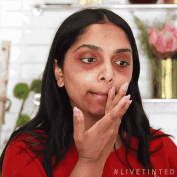 gif of Deepica Mutyala applying a red huestick corrector to their face and then applying foundation over it