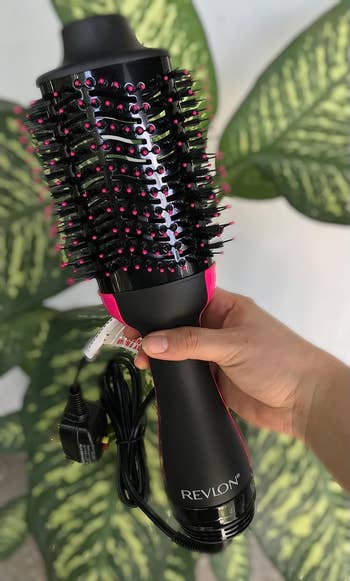 reviewer holding their black blow dryer brush with pink detail