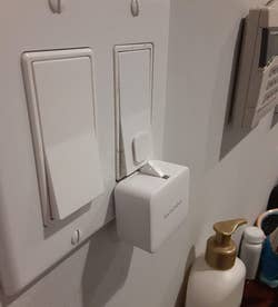  a reviewer photo of the white SwitchBot mounted on a light switch 