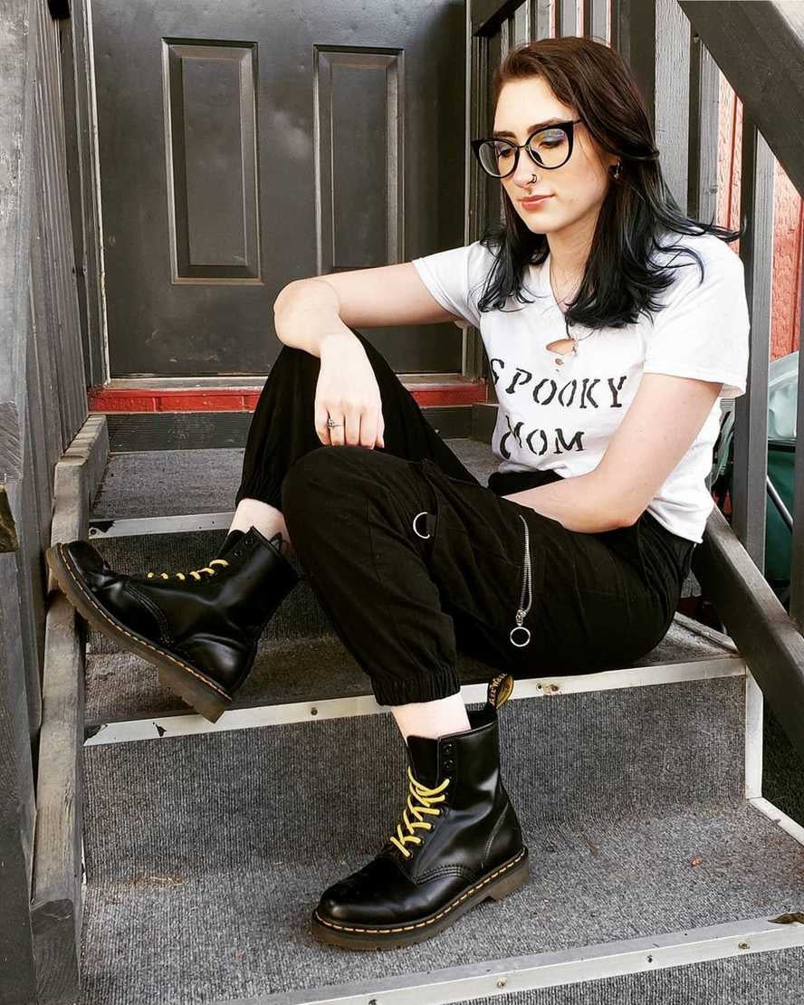 model wearing black doc martens while sitting on a stoop