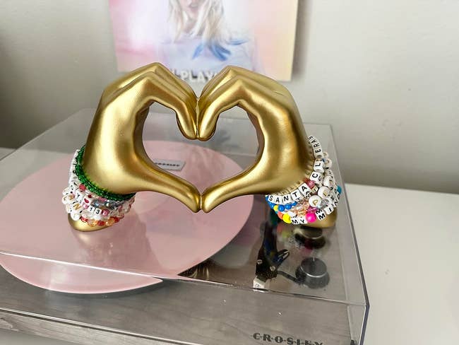 reviewer representation of 2 hands forming bosom statuette with beaded bracelets from Taylor Swift's Eras tour