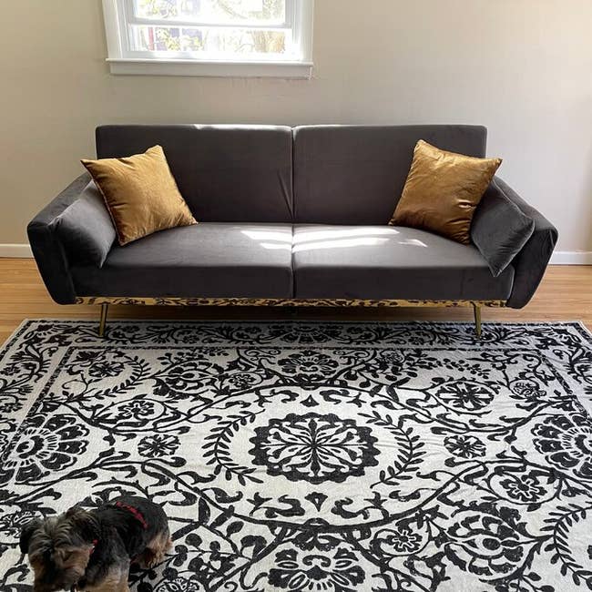 reviewer photo of a gray velvet futon with two yellow throw pillows on it